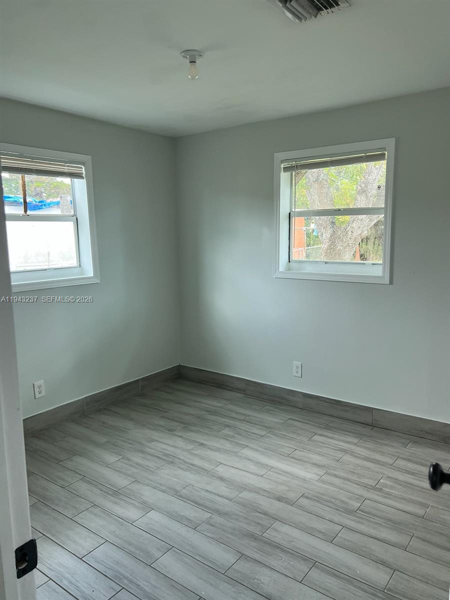 2627 Northwest 3rd Street Pompano Beach, FL 33069 - Photo 6 of 9 an empty room with wooden floor and windows