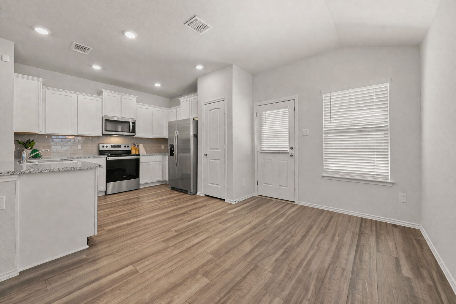 108 Pivot Drive Taylor, TX 76574 - Photo 10 of 30 a kitchen with stainless steel appliances granite countertop a refrigerator oven a sink dishwasher and white cabinets with wooden floor