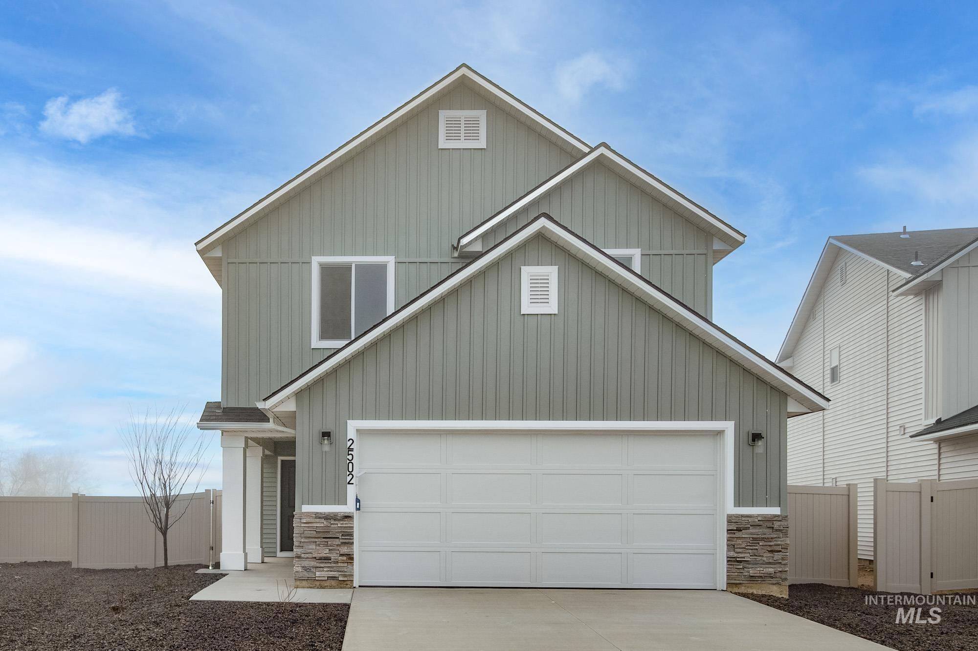 View of front facade featuring stone siding, board and batten siding, concrete driveway, and a garage