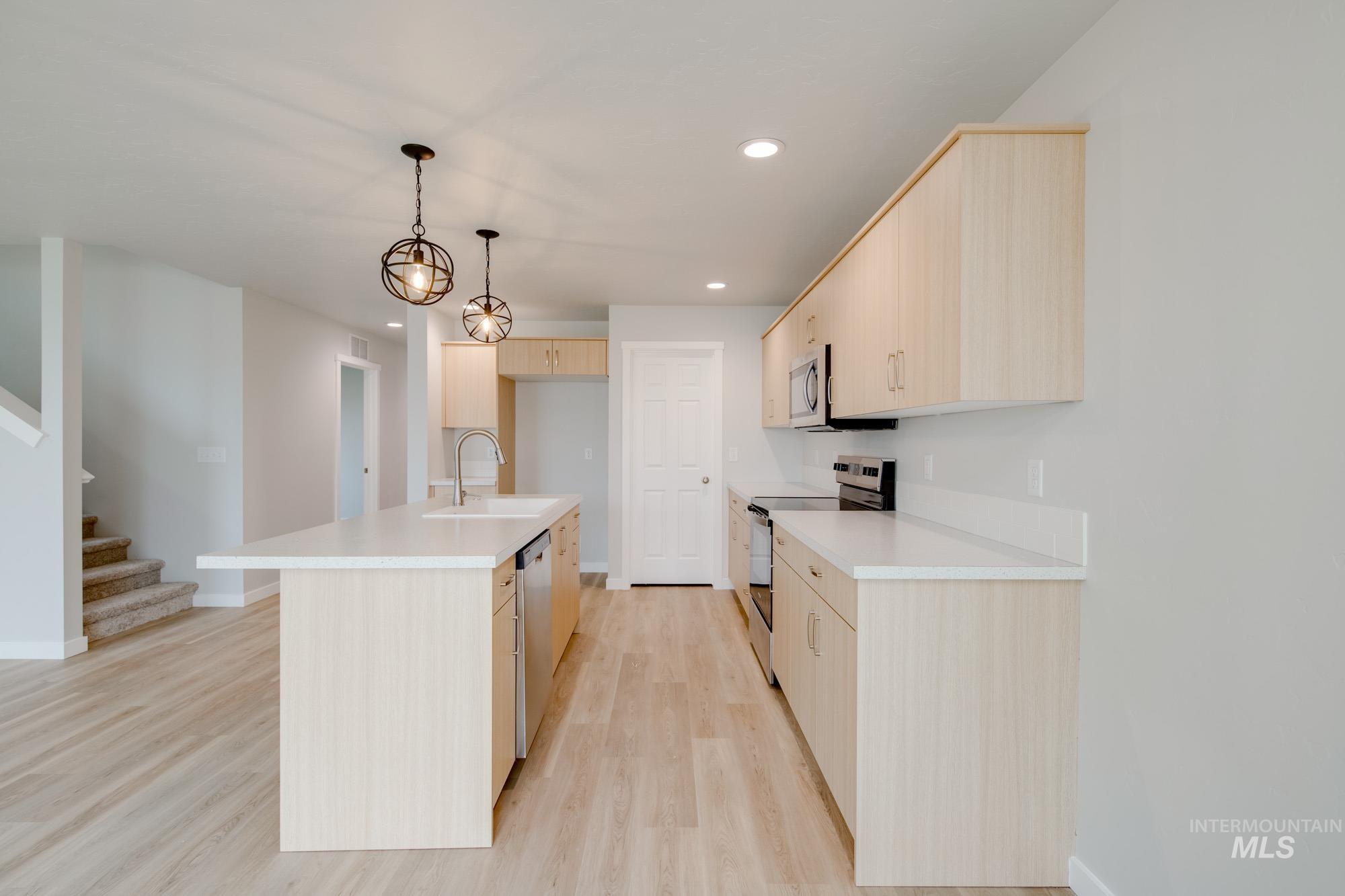 2502 West Fallon Loop Nampa, ID 83651 - Photo 6 of 21 Kitchen featuring light countertops, appliances with stainless steel finishes, light brown cabinets, light wood finished floors, and a center island with sink