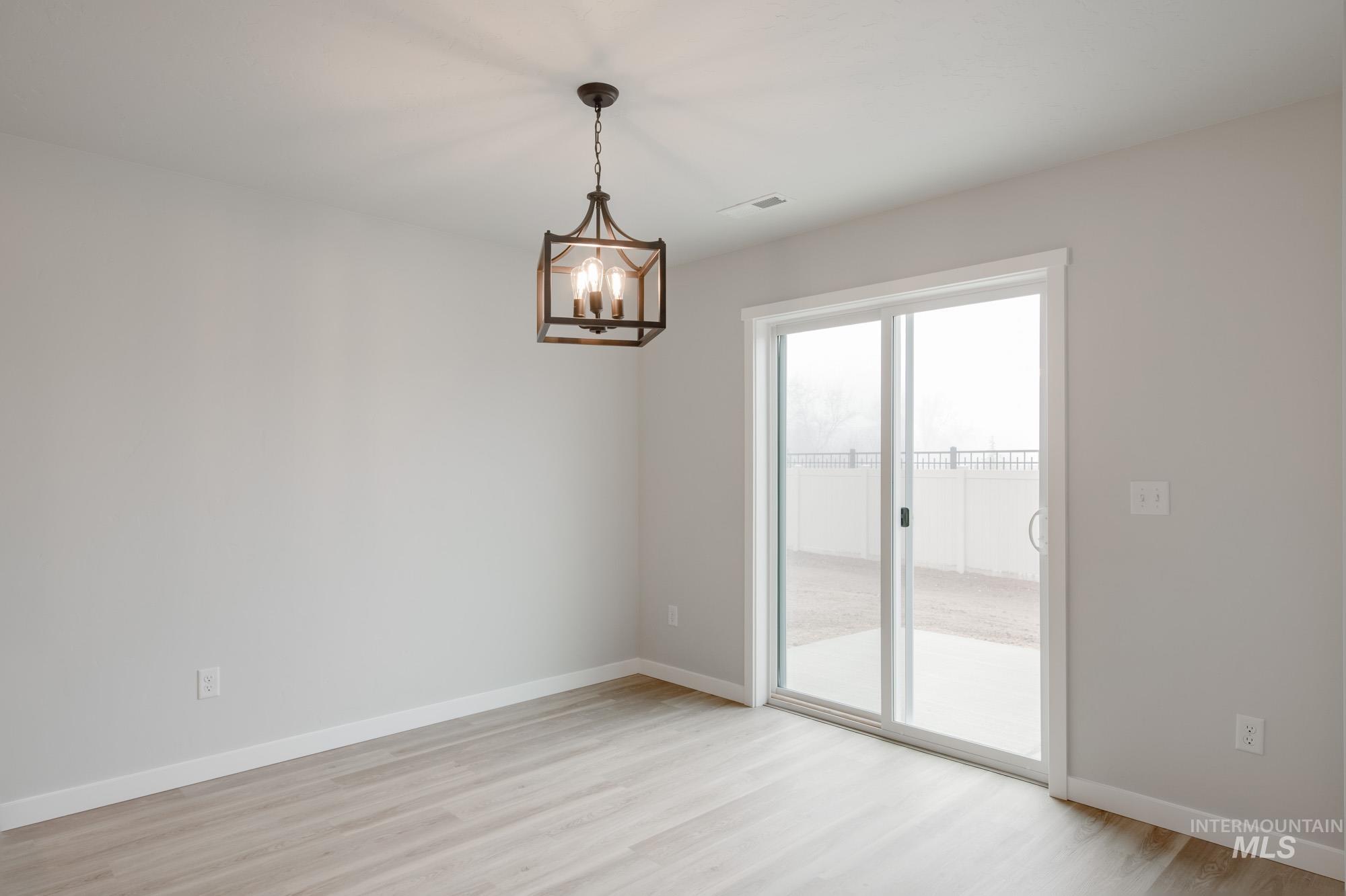 2502 West Fallon Loop Nampa, ID 83651 - Photo 9 of 21 Empty room with light wood finished floors and a chandelier