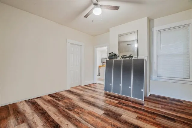 an empty room with wooden floor cabinet and windows