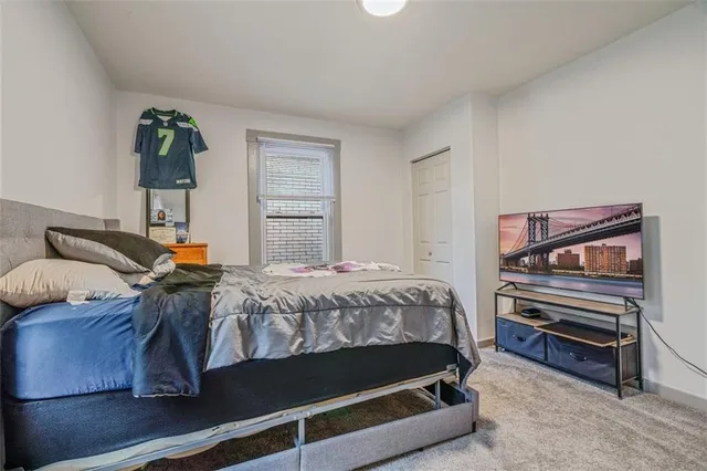 a bedroom with a bed a dresser and next to a window