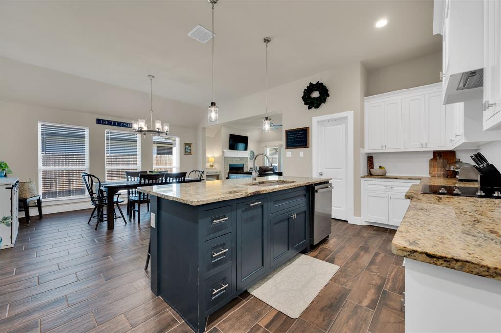 1313 Ridgeview Drive Weatherford, TX 76086 - Photo 11 of 34 Kitchen with two tone cabinetry, light stone countertops, a kitchen island with sink, wood tiled floors, and a kitchen bar