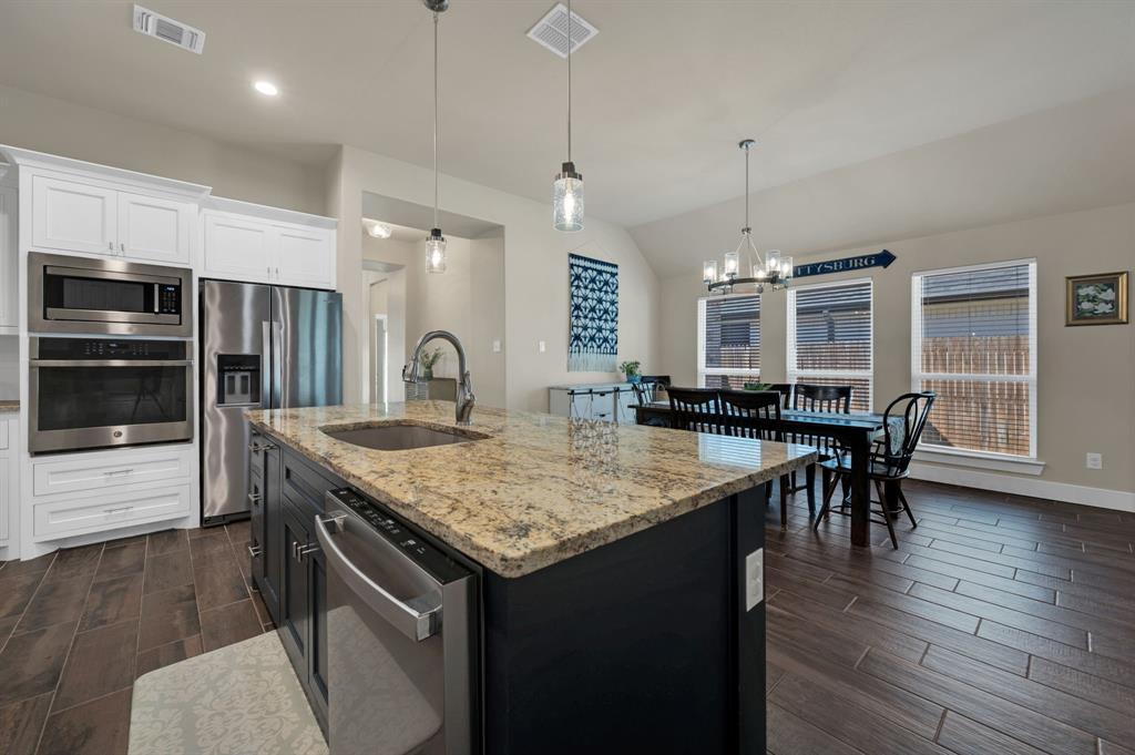 1313 Ridgeview Drive Weatherford, TX 76086 - Photo 13 of 34 Dual tone kitchen featuring wood finish floors, two tone cabinets, stainless steel appliances, light stone counters, and lofted ceiling
