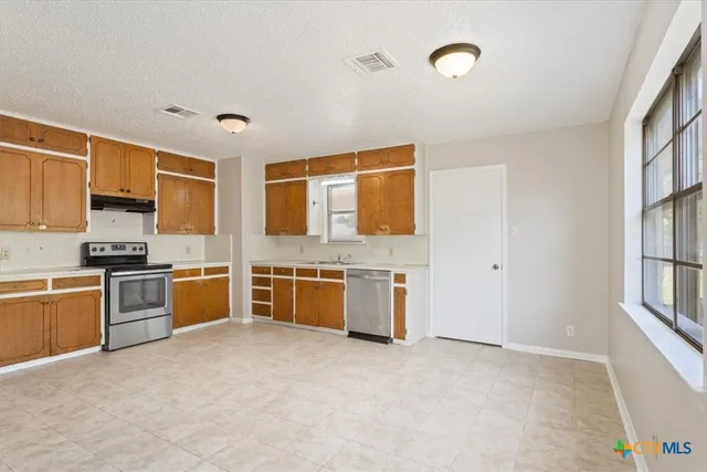 a large kitchen with stainless steel appliances granite countertop a stove and a sink