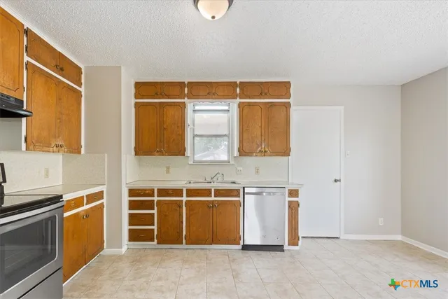 a view of a kitchen with stainless steel appliances wooden floor and a sink