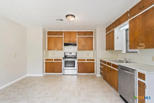 a kitchen with stainless steel appliances a stove a sink and a refrigerator
