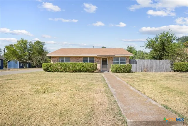 a front view of house with yard and trees in the background