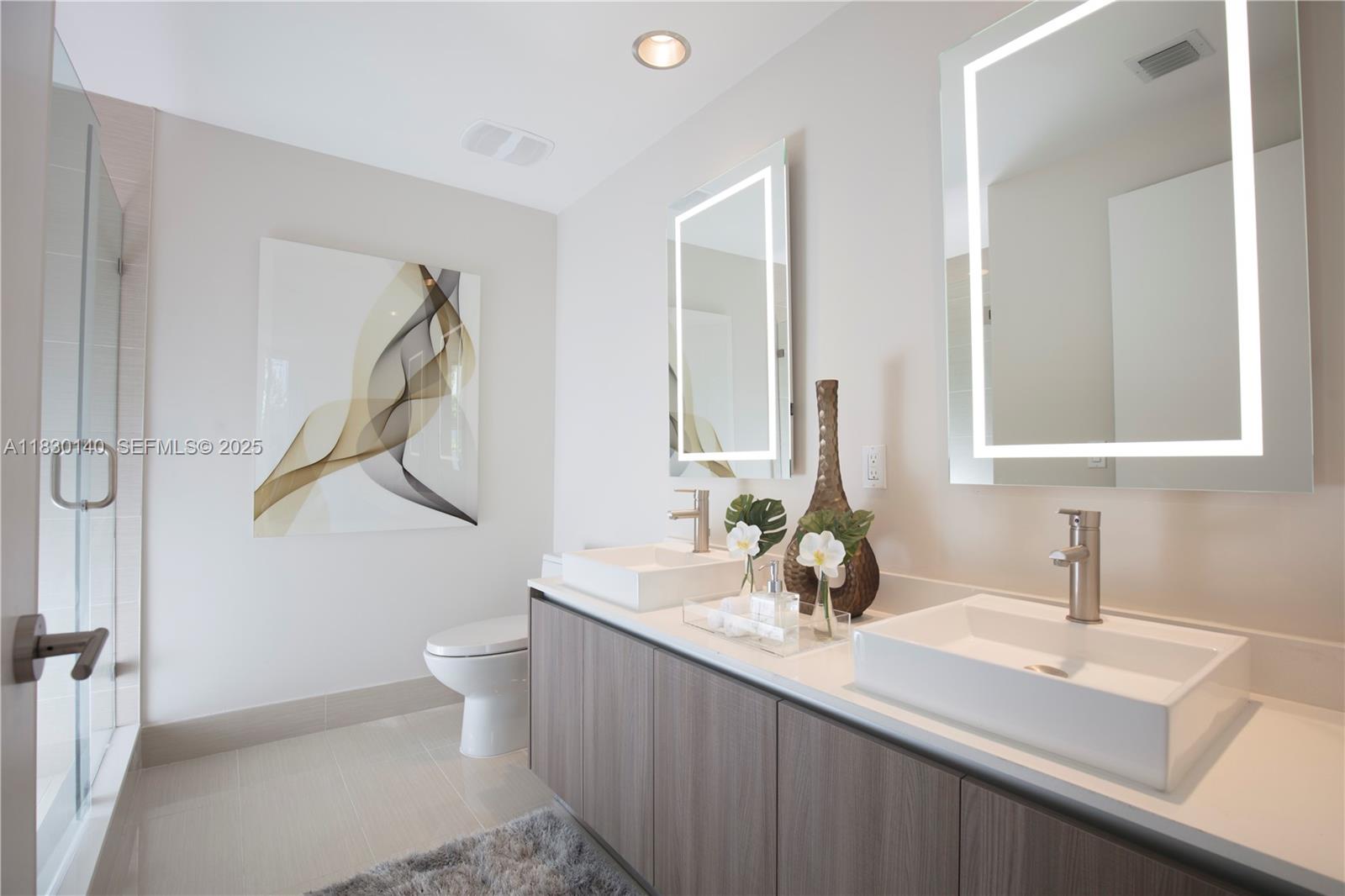 201 Southwest 17th Road, Unit 307 Miami, FL 33129 - Photo 23 of 26 a bathroom with a double vanity sink and a mirror