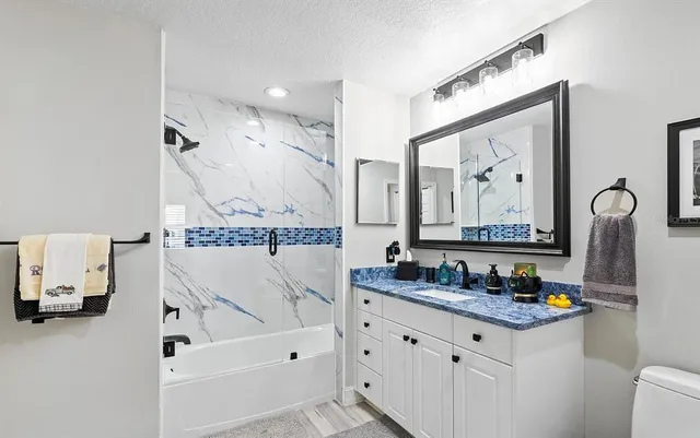 a bathroom with a granite countertop tub sink and mirror
