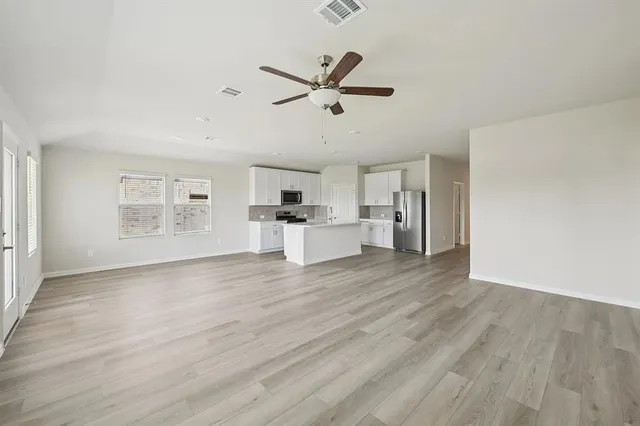 a view of empty room with wooden floor and ceiling fan