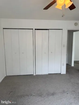 an empty room with windows and a chandelier fan