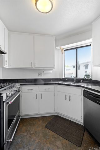 a kitchen with granite countertop a stove a sink and a white cabinets