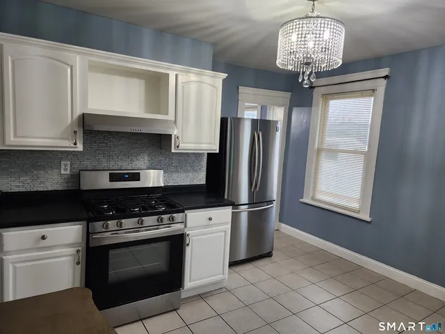 a kitchen with stainless steel appliances granite countertop a stove a refrigerator and a white cabinets