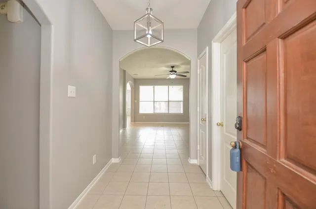 a view of a hallway with wooden floor and a chandelier
