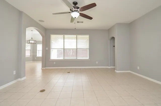 a view of an empty room with a window and a kitchen