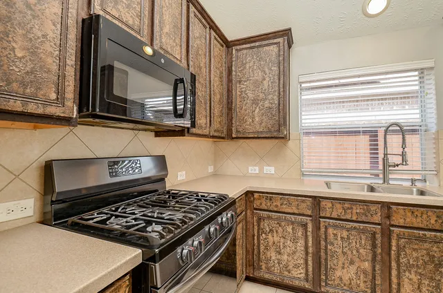 a kitchen with stainless steel appliances granite countertop a stove a sink and a microwave