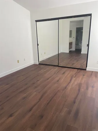 an empty room with wooden floor and mirror