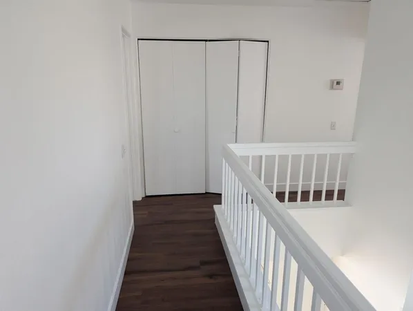 a view of a hallway with wooden floor and staircase