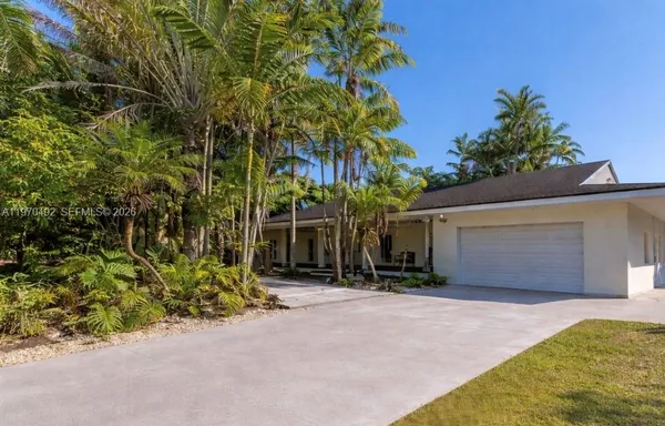 front view of house with a yard and trees