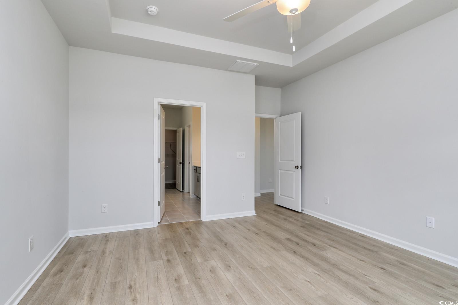 331 Garden Grove Street Conway, SC 29526 - Photo 11 of 24 Unfurnished bedroom with a raised ceiling, light wood-style floors, ensuite bathroom, and a ceiling fan