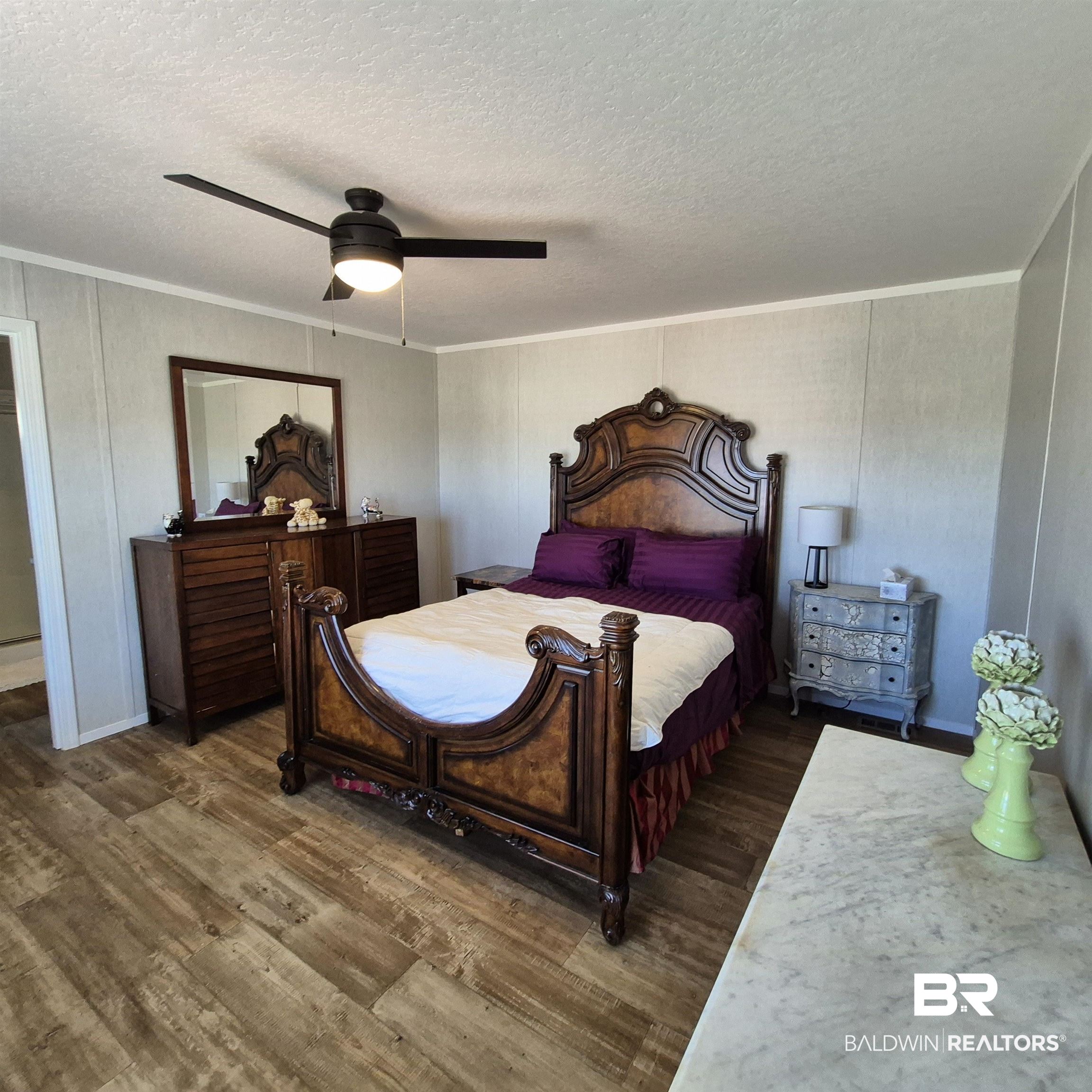 8867 Old Stage Road Repton, AL 36475 - Photo 16 of 37 Bedroom featuring dark wood-style floors, ceiling fan, a textured ceiling, and crown molding