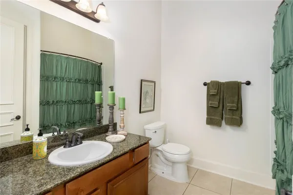 a bathroom with a granite countertop sink a toilet and mirror