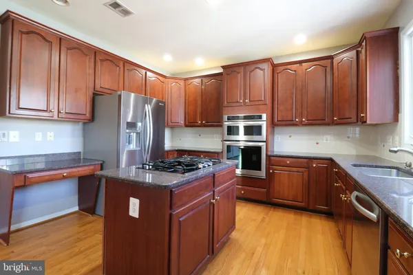 a kitchen with stainless steel appliances granite countertop a stove refrigerator sink and cabinets