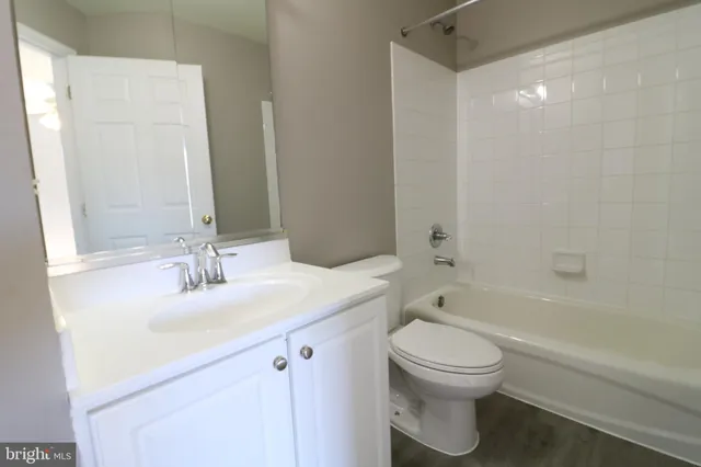 a bathroom with a bathtub shower sink vanity mirror and toilet