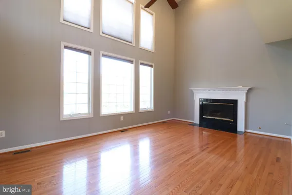 an empty room with wooden floor fireplace and windows