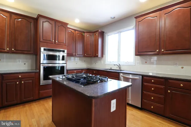 a kitchen with stainless steel appliances granite countertop wooden cabinets a stove top oven a sink and dishwasher