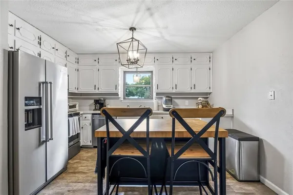 a kitchen with stainless steel appliances a table chairs and refrigerator