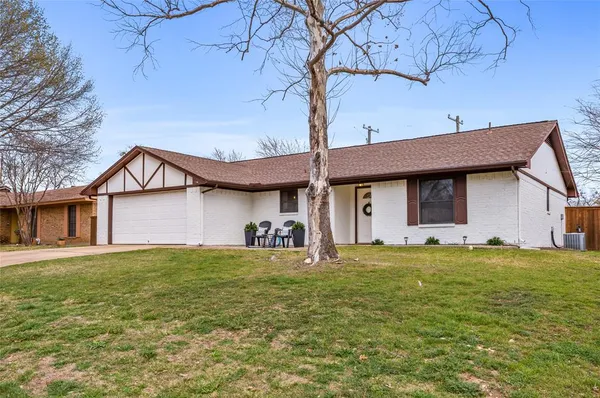 a view of a house with a yard and a large tree