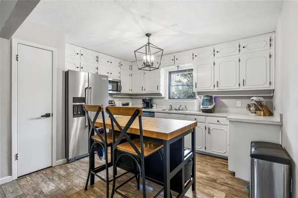 a kitchen with stainless steel appliances granite countertop a dining table chairs refrigerator and sink