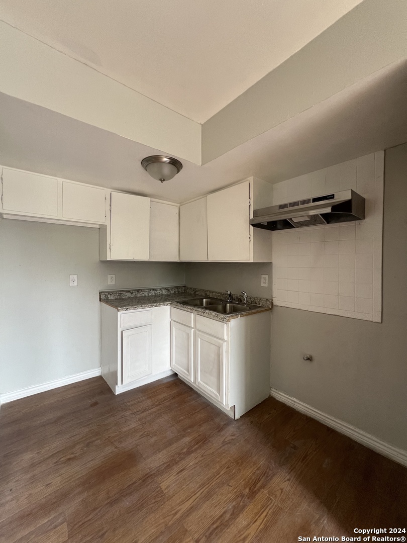 1723 West Mayfield Boulevard, Unit 5 San Antonio, TX 78211 - Photo 4 of 13 a kitchen with granite countertop white cabinets and black appliances