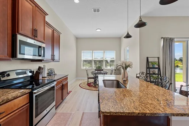 a kitchen with granite countertop kitchen island stainless steel appliances a stove a sink a microwave oven a counter top space and cabinets