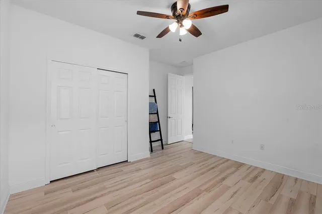 an empty room with wooden floor and a ceiling fan