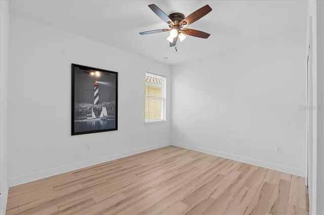 a view of a big room with wooden floor and a chandelier fan