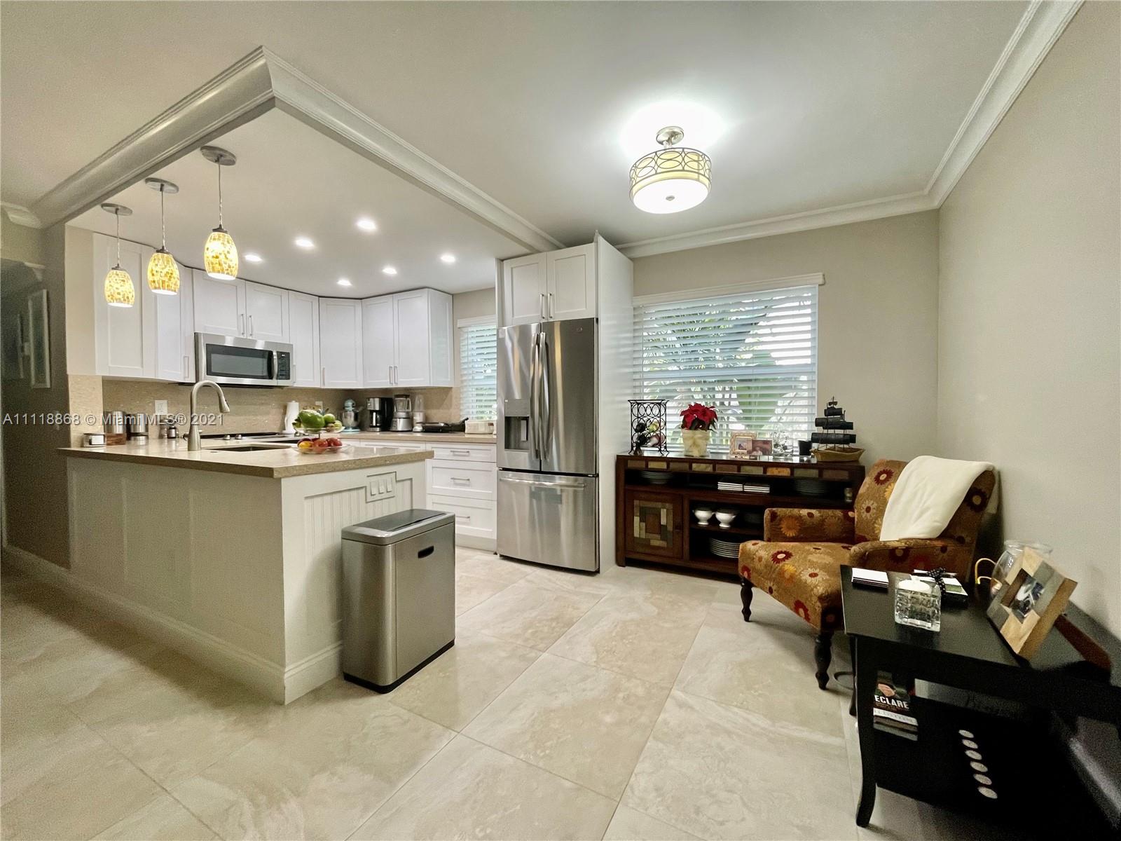 Kings Point Piedmont Delray Beach, FL 33484 - Photo 8 of 22 a kitchen with a refrigerator a sink dishwasher a stove and a dining table with wooden floor