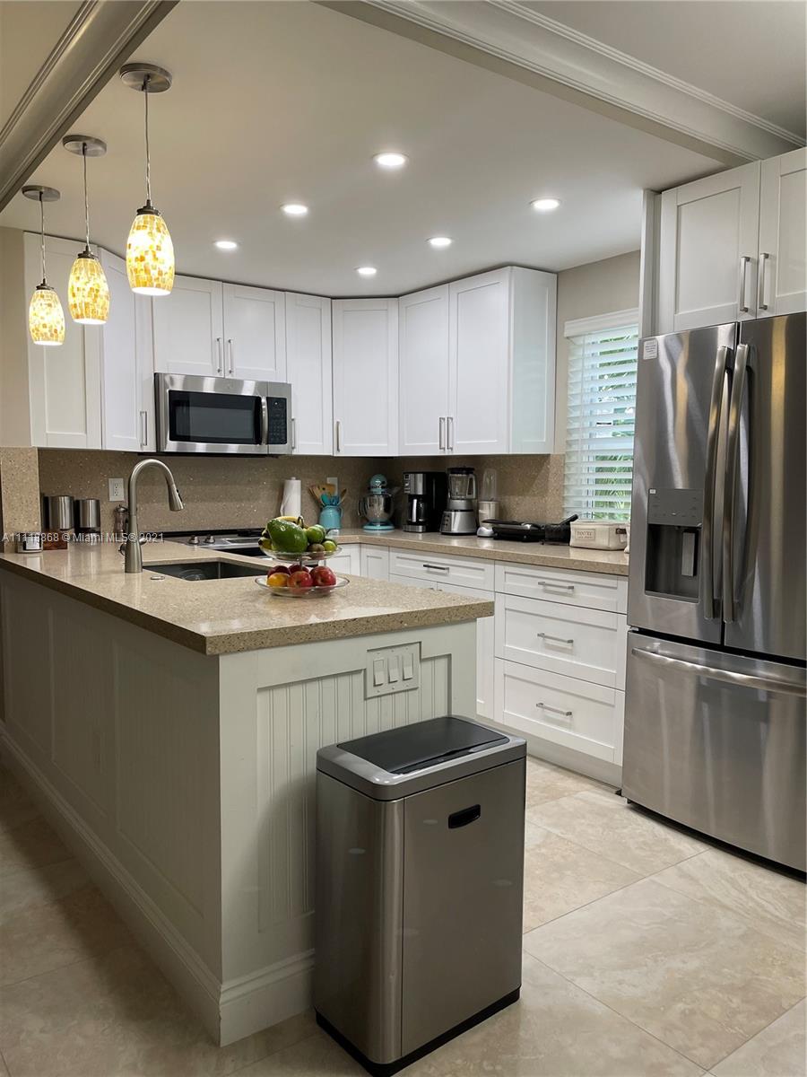 Kings Point Piedmont Delray Beach, FL 33484 - Photo 10 of 22 a kitchen with kitchen island granite countertop a stove a sink a refrigerator and a microwave