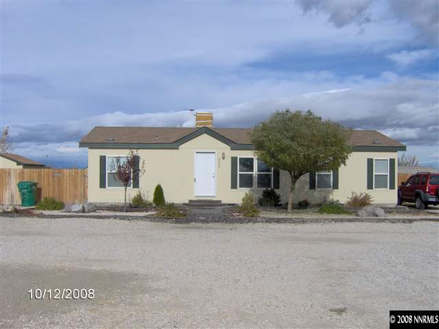 a front view of house with yard and trees in the background