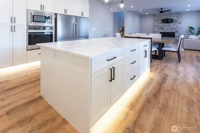 a open kitchen with kitchen island white cabinets and stainless steel appliances