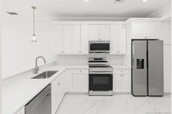 a kitchen with stainless steel appliances a refrigerator sink and white cabinets