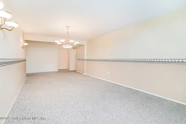 an empty room with chandelier fan and windows