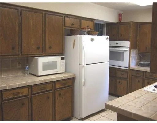 a kitchen with kitchen island wooden cabinets and refrigerator