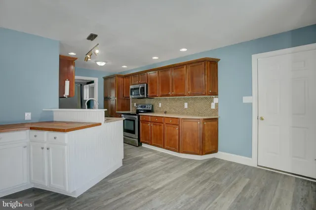 a kitchen with stainless steel appliances granite countertop a sink counter space cabinets and wooden floor