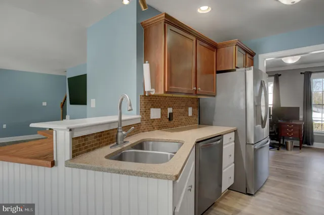 a kitchen with stainless steel appliances granite countertop a sink and a refrigerator