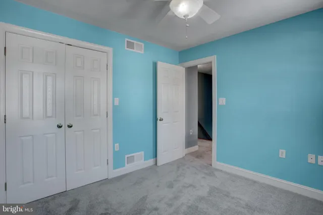 an empty room with windows and chandelier fan
