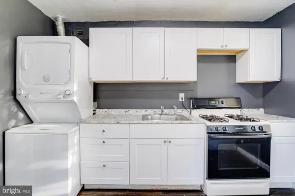 a kitchen with granite countertop a sink a stove and cabinets
